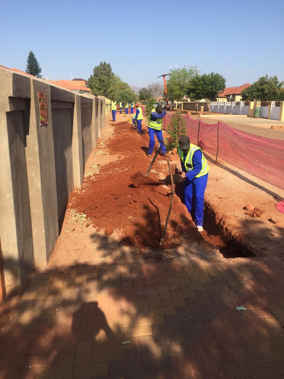 Team excavating a trench for network cabling along a residential street